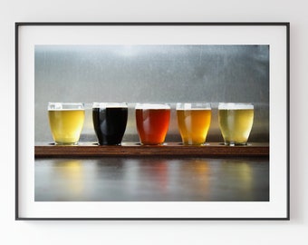 以下が含まれることがあります： 木製の表面に並んだ、透明なグラスに入った6種類のビール。ビールの色は、薄い金色から濃い茶色まで様々です。