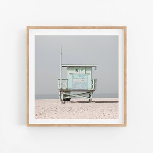 May include: A light blue lifeguard stand with a white sign that reads "5 ST" on a sandy beach.