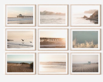 Op de afbeelding: Negen ingelijste prints van strandlandschappen. De afbeeldingen tonen oceaanscènes met pieren, golven en kustgezichten. Het kleurenpalet is zacht, met warme tinten beige, bruin en blauw. De frames zijn licht van kleur, en de algehele esthetiek is sereen en kalmerend.