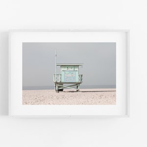 May include: A light blue lifeguard stand on a sandy beach with a cloudy sky in the background. The stand has a sign that reads "51 ST".