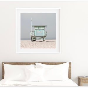 May include: A light blue lifeguard stand on a sandy beach with a gray sky in the background.