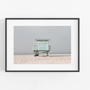 May include: A light blue lifeguard stand on a sandy beach with a gray sky in the background. The stand has a sign that reads "51 ST".