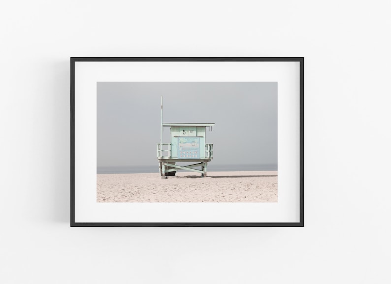 May include: A light blue lifeguard stand on a sandy beach with a gray sky in the background. The stand has a sign that reads "51 ST".