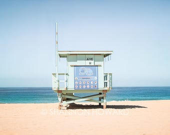May include: A light blue lifeguard stand on a sandy beach with a blue ocean in the background. The stand has a sign that reads "Currents Can Be Your Worst Enemy".