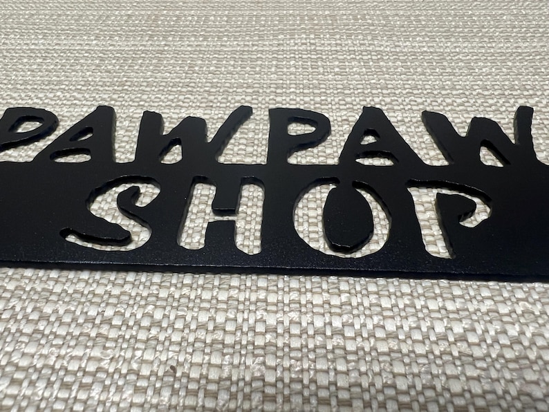 May include: Black metal sign with the words "Paw Paw Shop" cut out in a whimsical font.