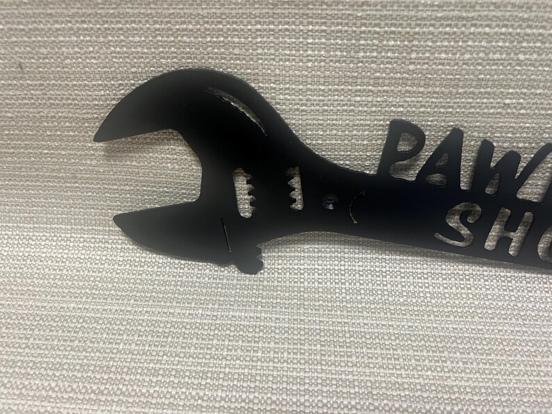 May include: Black metal wrench with the words "Paw Shop" cut out.