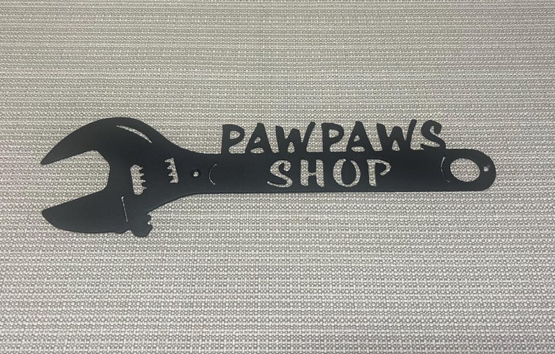 May include: Black metal wrench shaped sign with the text "Paw Paws Shop" cut out.
