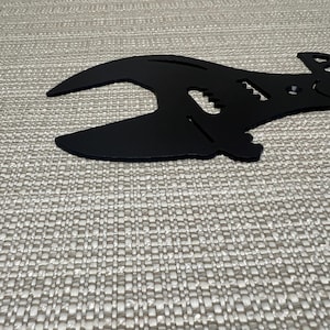 May include: Black metal wrench shaped like a guitar with the word "Papa" cut out of the metal.