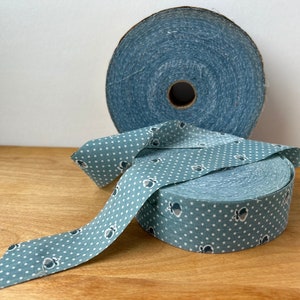 May include: Two spools of blue and white patterned fabric ribbon. One spool is plain blue and the other has white polka dots and a small blue design.