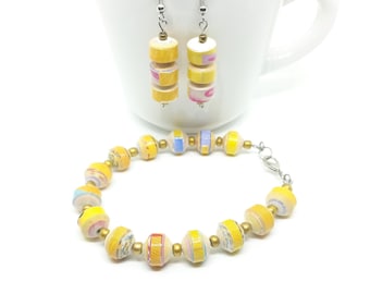 May include: A set of yellow and white paper bead earrings and a bracelet. The earrings are made of three paper beads each, and the bracelet is made of 10 paper beads. The beads are all different colors and patterns.