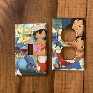May include: Two decorative light switch covers featuring characters from the animated film Lilo & Stitch. One cover has a single switch opening, and the other has two outlet openings. The covers are decorated with colorful images of Stitch and Lilo.