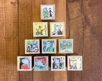 May include: A set of ten wooden blocks with colorful illustrations of an elephant, a monkey, and a man with an umbrella. The blocks are arranged in a pyramid shape.