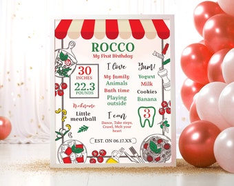 Op de afbeelding: Een ingelijst verjaardagsbord met de naam "Rocco" en de tekst "My First Birthday". Het bord bevat de afmetingen 76,2 cm en 10,1 kg. Decoratieve ballonnen in rood en wit staan op de achtergrond.