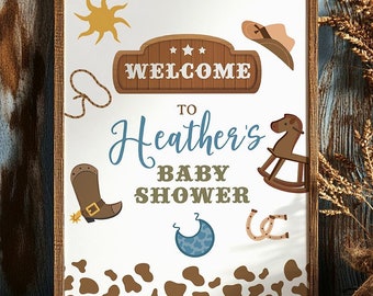 May include: A welcome sign for a baby shower with a cowboy theme. The sign is white with brown and blue accents. It says "Welcome to Heather's Baby Shower".
