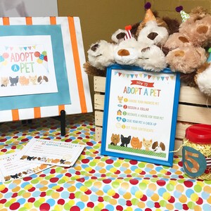 May include: A table with a colorful polka dot tablecloth. There are stuffed animals in a wooden crate, a sign that says "How to Adopt a Pet", and a sign that says "Adopt a Pet".