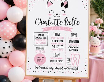 May include: A white sign on an easel with the text "Charlotte Belle" and "My First Birthday." The sign includes the child's height (30 inches) and weight (22 pounds). Pink, black, and white balloons are in the background.