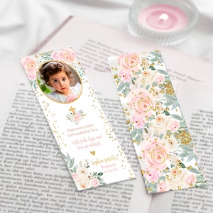 May include: A white bookmark with a pink floral design and gold glitter. The bookmark features a photo of a baby girl and the text "Baptized in faith, surrounded by love. With faith, hope and love, we celebrate."  "Sophin Isabelle's Baptism 11/25/XX"