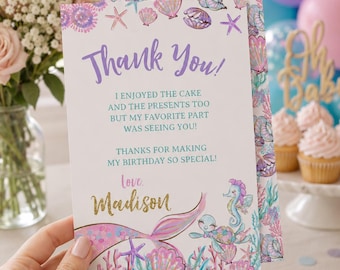 May include: A mermaid-themed thank you card with the text "Thank You!" in purple script. The card features illustrations of seashells, starfish, and a mermaid tail in pastel colors. The card reads "Love, Madison."
