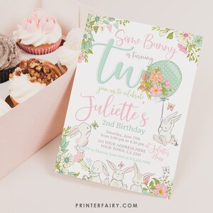 May include: A birthday invitation with the text "Some Bunny is turning Two" in a whimsical font. The invitation features illustrations of bunnies, flowers, and a balloon. Cupcakes are in the background.