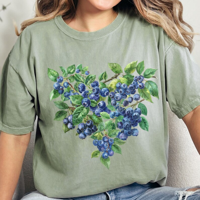 May include: A green t-shirt with a watercolor illustration of blueberries and leaves in the shape of a heart.