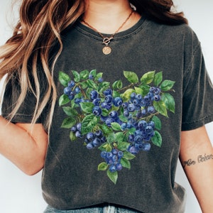May include: A dark gray t-shirt with a watercolor illustration of blueberries in a heart shape.