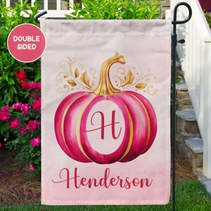 May include: Pink and gold watercolor pumpkin with the letter H and the name Henderson on a pink background.  Double-sided garden flag.