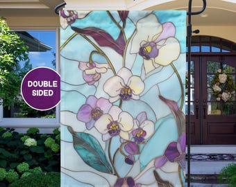 May include: Double-sided garden flag featuring a stained-glass design of orchids in shades of white, purple, and yellow against a light blue background. The flag is displayed on a black metal stand, perfect for outdoor decor.