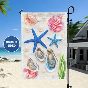 May include: A double-sided garden flag with a beach theme. The flag features a white background with blue starfish, pink and white seashells, and oyster shells with blue interiors. The flag is perfect for adding a touch of coastal charm to your outdoor space.