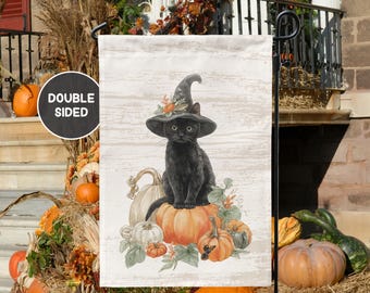 May include: A double-sided garden flag featuring a black cat wearing a witch hat, sitting atop pumpkins. The flag has a light wood grain background. Pumpkins and fall foliage surround the cat. The flag is designed for outdoor use.