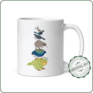 May include: White ceramic mug with a colorful illustration of New Zealand birds stacked on top of each other. The birds are labeled with their names:  Tui, Kakako, Kiwi, Takahe, and Kakapo. The mug has a green circle stamp that says "Designed by Artist Original Art Designed by Artist".