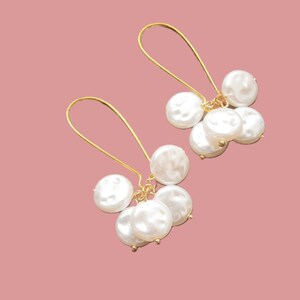 May include: A pair of gold dangle earrings with multiple white pearl drops.