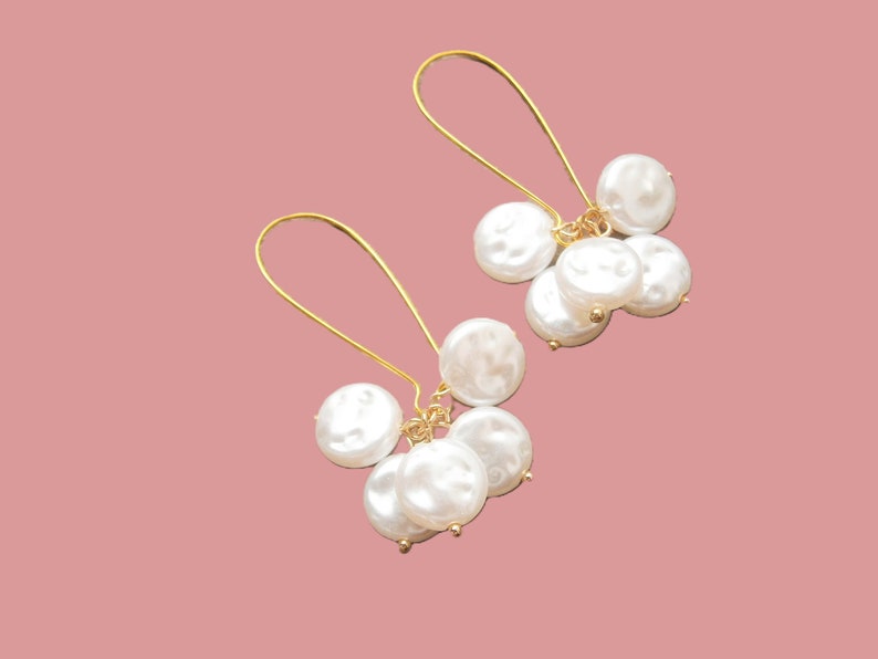 May include: A pair of gold dangle earrings with multiple white pearl drops.