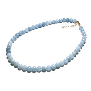 Könnte beinhalten: Eine zarte Halskette mit hellblauen Aquamarinperlen. Die runden Perlen sind aufgereiht und bilden ein glattes, elegantes Design. Die Halskette hat einen goldfarbenen Verschluss und eine Verlängerungskette.