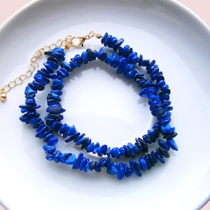 May include: A double strand necklace made of blue gemstone chips with a gold chain clasp.