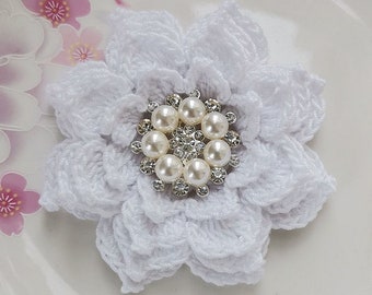 May include: A white crocheted flower with a pearl and rhinestone embellishment in the center.