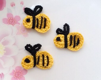 Peut inclure: Trois abeilles crochetées jaunes et noires avec des ailes noires sur un fond blanc.