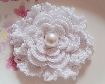 May include: A white crocheted flower with a pearl in the center.