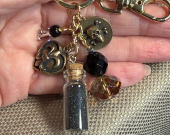 Charm de calavera pirata dorada / Accesorio para bolso con flor de lis, llavero con vial de arena negra