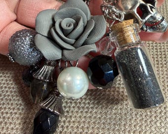 Llavero con dije de calavera y frasco de arena negra, accesorio original y divertido para bolso.