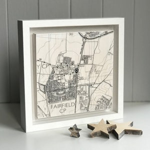 May include: A framed map print of Fairfield Hall, in a white frame. The black and white map shows the area with the text "Fairfield Hall" and "Fairfield CP". Three wooden star decorations are in front of the frame.