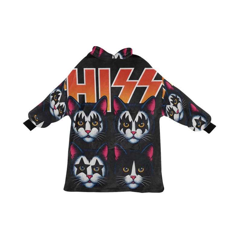 Puede incluir: Manta con capucha negra con un patr&oacute;n repetido de caras de gato maquilladas, que recuerdan a la banda KISS. La palabra "KISS" est&aacute; impresa en naranja y blanco. La manta tiene mangas largas y una capucha.