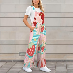 Puede incluir: Un mono colorido con un estampado de fresas y lazos. El mono tiene un diseño de patchwork con patrones de cuadros rojos, rosas y azules. Las correas son de color azul claro y el atuendo se combina con una camiseta blanca y zapatillas blancas.