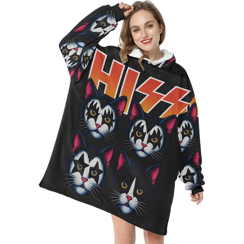 Puede incluir: Sudadera con capucha negra de gran tama&ntilde;o con un patr&oacute;n repetido de caras de gato con maquillaje, que recuerda a la banda KISS. La palabra "KISS" est&aacute; impresa en naranja y blanco. Las mangas tambi&eacute;n tienen dise&ntilde;os de caras de gato.