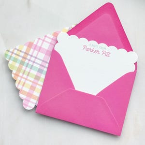 May include: A bright pink envelope with a white scalloped-edge card inside. The card has the text "A NOTE FROM Parker Pitt" printed in pink. A second card with a pastel plaid pattern is visible.