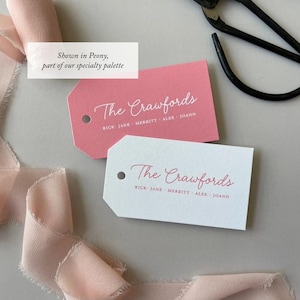 May include: Two rectangular paper gift tags with angled corners and a hole punch. One tag is pink with white text, the other is white with pink text. Both feature the script text The Crawfords and the names Rick, Jane, Merritt, Alex, Joann.
