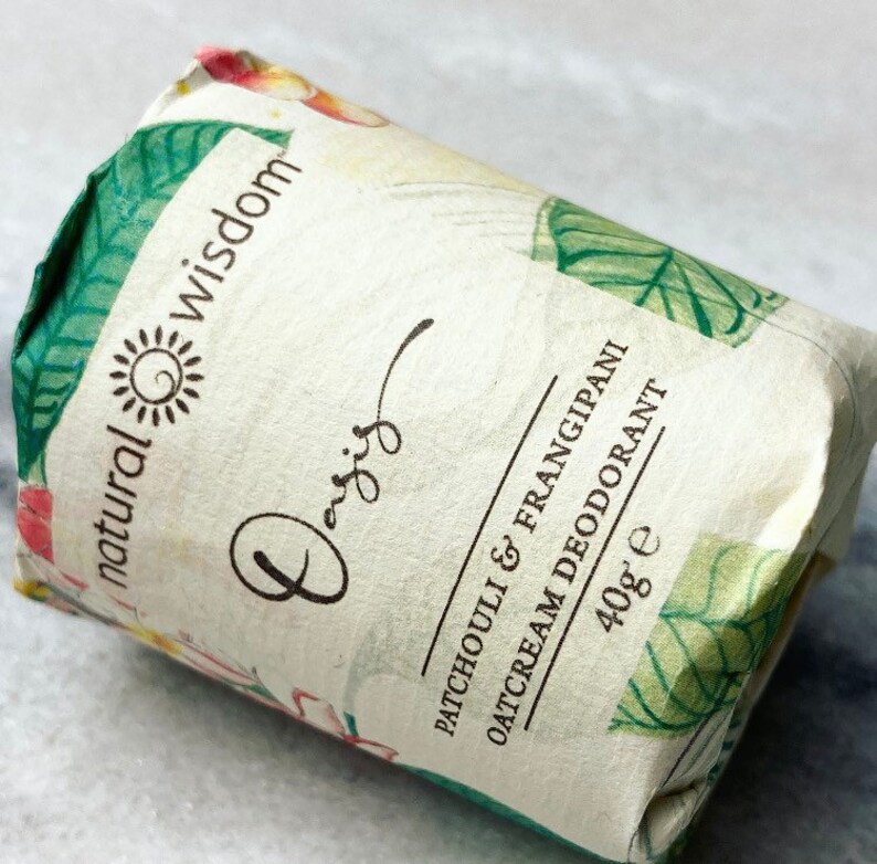 May include: A white tube with green and floral designs. The tube is labeled "natural wisdom" and "Patchouli & Frangipani Oatcream Deodorant 40g e".
