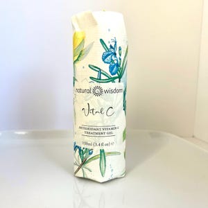 May include: A white tube with a green and blue floral design. The tube is labeled "natural wisdom Vital C ANTIOXIDANT VITAMIN C TREATMENT GEL 100ml (3.4 fl oz) e"
