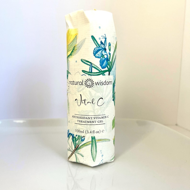 May include: A white tube with a green and blue floral design. The tube is labeled "natural wisdom Vital C ANTIOXIDANT VITAMIN C TREATMENT GEL 100ml (3.4 fl oz) e"