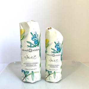 May include: Two bottles of natural wisdom Vital C Antioxidant Vitamin C Treatment Gel. The smaller bottle is 50ml (1.8 fl oz) and the larger bottle is 100ml (3.4 fl oz). Both bottles have a white background with a floral design and the text "natural wisdom" and "Vital C" in blue and yellow.