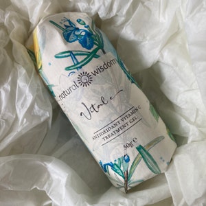 May include: A white tube with a floral design and the text "natural wisdom Vitale Antioxidant Vitamin C Treatment Gel 50g e" printed on it.